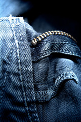 Metal stained brass zipper with slider blue denim background / close up