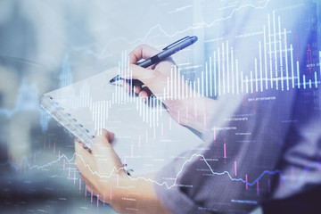 Multi exposure of hands making notes with forex chart huds. Stock market concept.