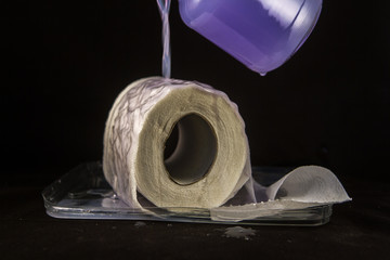 Unrolled toilet paper that gets wet and absorbs the liquid on a black background