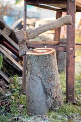 Old rusty ax stuck in a wooden stump.