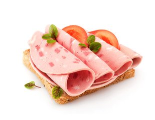 Sandwich with sliced sausage on white bread, with tomatoes and herbs.