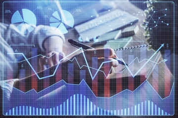 Financial forex charts displayed on woman's hand taking notes background. Concept of research. Double exposure