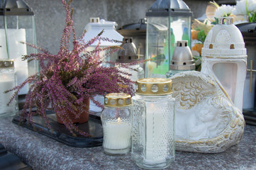 Monument and candles in the cemetery. All Saints Day in Poland. Icon lamp with angels.