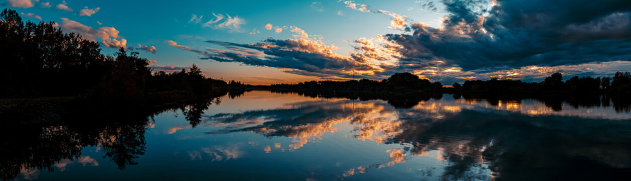 High resolution stitched panorama of a beautiful sunset with arrow-shaped reflections near Plattling, Isar, Bavaria, Germany
