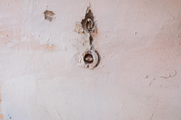 Texture of a white and pink wall in cracks with an old switch, photo wallpaper, photophone, background. Flat lay. Copy space. The old wall.