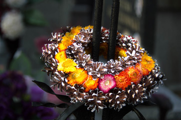 Monument and candles in the cemetery. All Saints Day in Poland. Funeral wreath. Needles. Funeral flowers.