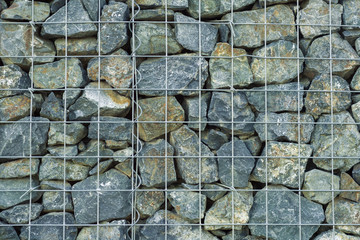 interesting creative background of gray granite stones behind a lattice of thin metal rods