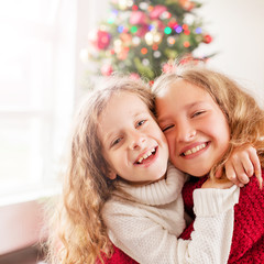 Two happy girl near christmas tree