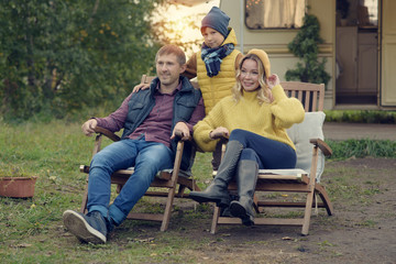 Mom, dad and son sitting on bench against caravan track, they like to travel together.  They are happy and enjoying their vacations.