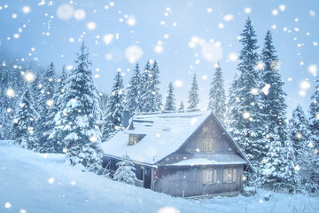 Christmas background. Winter scene with cozy wooden house in mountains in snowfall. Xmas scene. Winter landscape