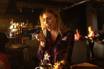 Positive woman eating salad at cozy cafe.
