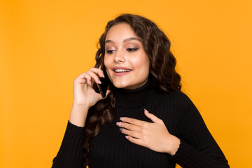Happy young woman talking phone isolated over the yellow background