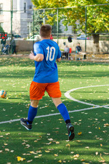 One soccer players performs an action play on a soccer field. All players wear unbranded clothes.