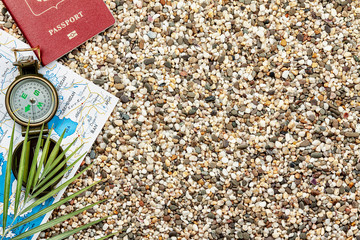 Compass, map, passport, fern, lie on the sea sand.