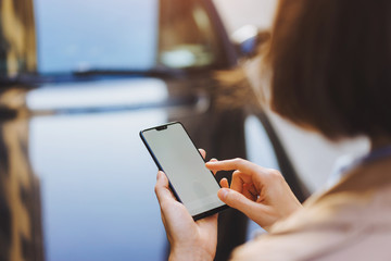 Back view from shoulder of female person looking to mock up copy space screen on mobile phone