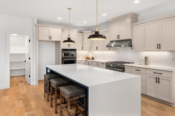 Beautiful kitchen in new luxury home with waterfall island, quartz counter tops, farmhouse sink, and hardwood floors.