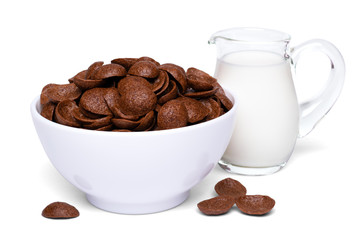 Crunchy chocolate corn flakes breakfast cereals in white bowl and milk in a glass jug