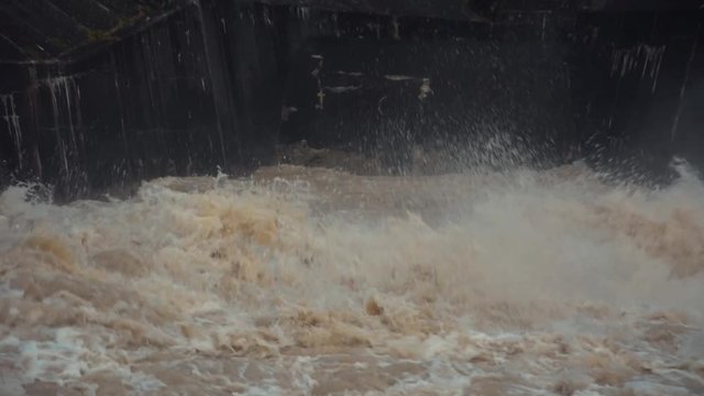 Low angle autumn flood water turbulent river with concrete walls in background