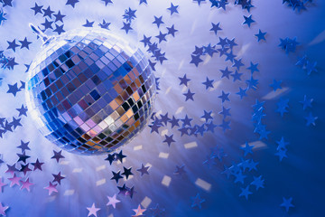 Christmas disco ball with rays on neon blue. Creative party background with copy space.