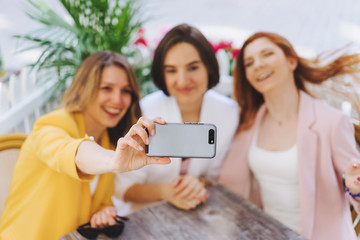 Cheerful female best friends posing for selfie on mobile for share in social networks sitting in cafe shop