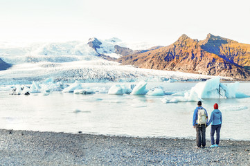 Icelandic landscape. Couple of tourist visiting the Fjallsarlon glacier and the lagoon at sunset.