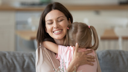 Caring happy mother embracing child daughter feeling tenderness at home