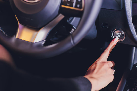woman female finger pressing the Engine start stop button of a car.