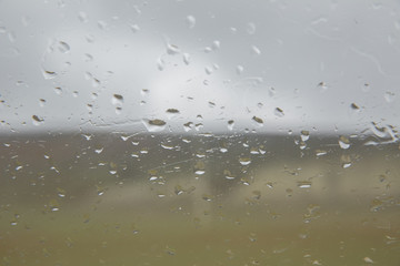 Rain drop on glass of the car road with fog or mist in green nature . Water drops on the glass in...