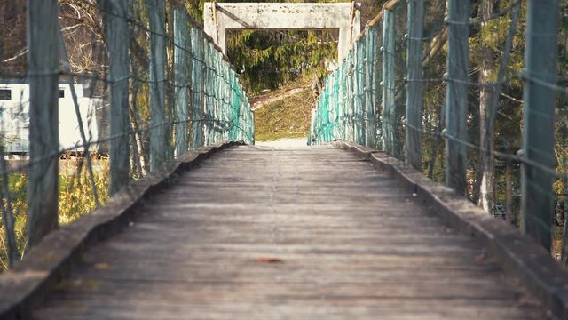 Low angle shaking rope suspension walking bridge with wooden decking over river