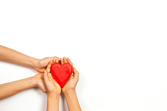 Adult And Child Hands Holding Red Heart Over White Background. Love, Healthcare, Family, Insurance, Donation Concept