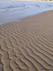 Obraz premium A tidal sandbar at low tide reveals natural wave patterns in sand shaped by water action hours before. Smithtown Bay, Long Island Sound, New York.