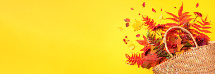 Autumn composition. Straw bag with autumn dried leaves on yellow background. Flat lay. Top view....