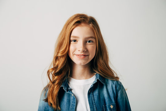 Red-haired pretty teenager girl smiling at the camera. Isolate on white background. Blue-eyed child with a benevolent emotion