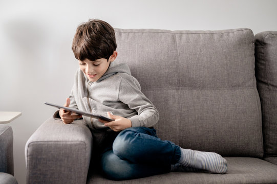 A boy concentrated playing with a tablet - Powered by Adobe