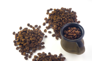  a clay cup filled with coffee beans next to three heaps of coffee beans on a white background