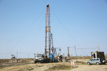 Land oil drilling rig blue sky .Land rig during the drilling operation . Oil and gas drilling rig onshore dessert with dramatic cloudscape .