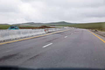 road receding into the distance in open countryside under a cloudy white sky with focus to the...