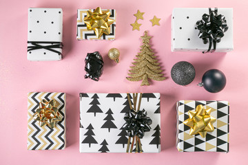 Selection of white, gold and black coloured christmas gift boxes on pink background