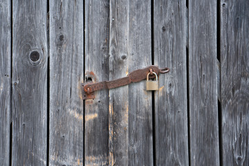 Detail of weathered planks of a shelter with a rusty padlock