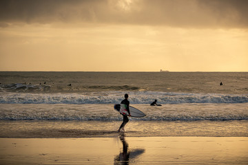 Fototapeta na wymiar Surfer on the beach at sunset, Caravelos beach, Portugal