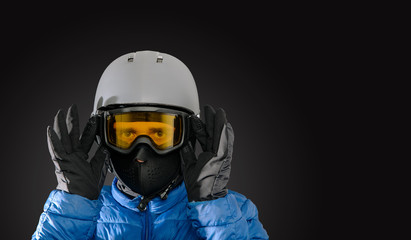 Skier wearing a ski helmet, google, gloves and a winter jacket on dark background. Concept of skiing, snowboarding. Winter sports.