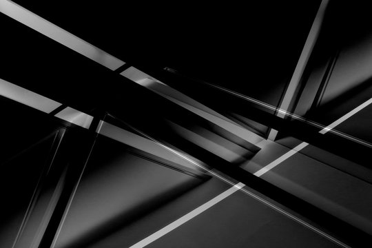 Fragment of modern architecture / interior with glowing lines in darkness. Abstract black geometric background with luminous angular / triangular structure in grunge style.