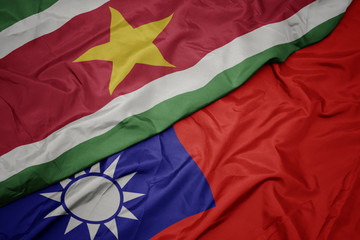 waving colorful flag of taiwan and national flag of suriname.