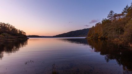 Sunrise at Loch Lomond, Scotland,UK..Beautiful landscape of Scottish Highlands.Tranquil morning scene with reflection of autumn coloured trees in calm lake surface.
