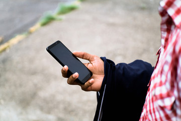 African American hand using the phone with black background on the sidewalk of a concrete street