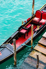Fototapeta na wymiar gondola moored near wooden poles awaiting tourists in Venice, Italy