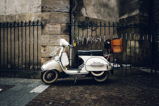 A vintage Vespa scooter parked in the street by a rainy day, in Nantes, France.