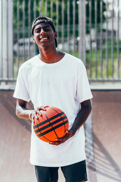 Cheerful African American player holding orange ball and looking at camera with wide smile