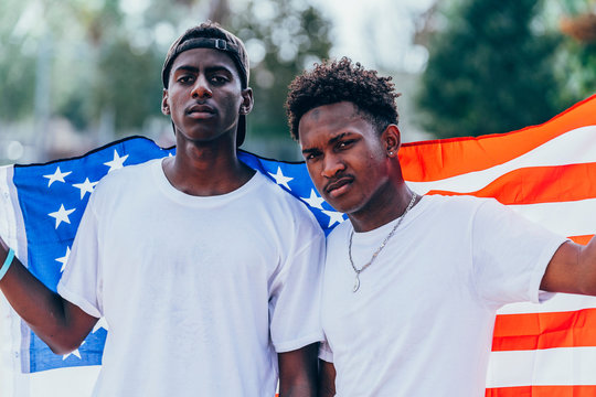 Serious African American men holding American flag on shoulder and looking away