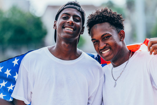 African American men holding American flag on shoulder and looking away